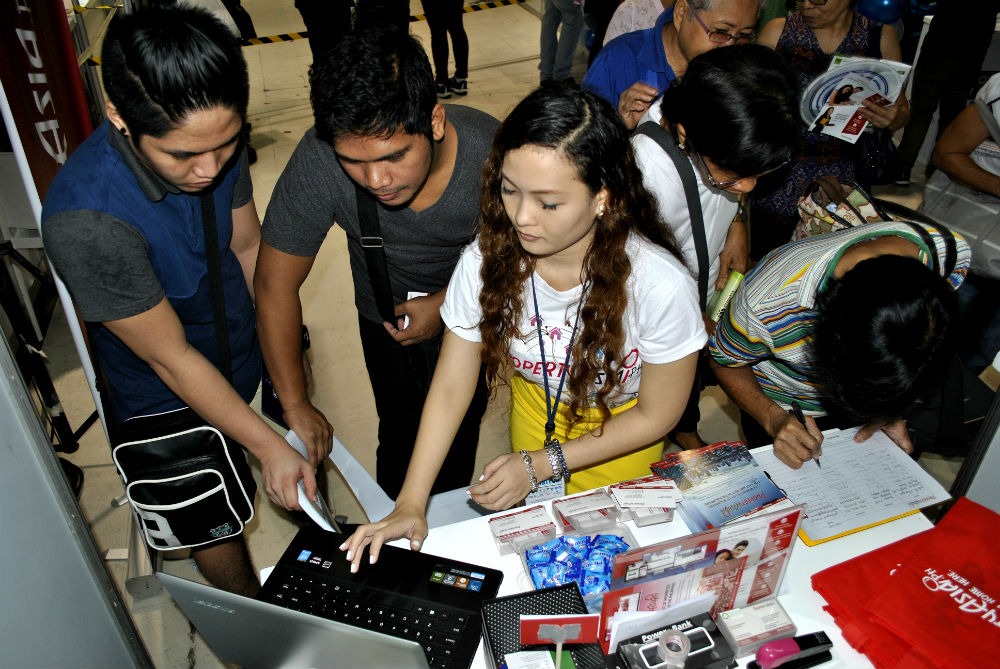 PropertyAsia.ph Marketing Assistant Jekelyn Nisola navigates the property search website with housing fair attendees (Photo: Oliver Oliveros)